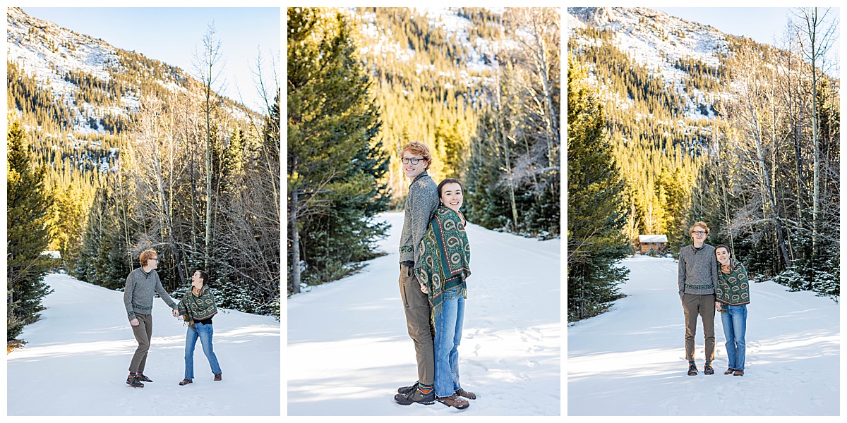 A couple poses in front of snow and pine trees for couple portraits.