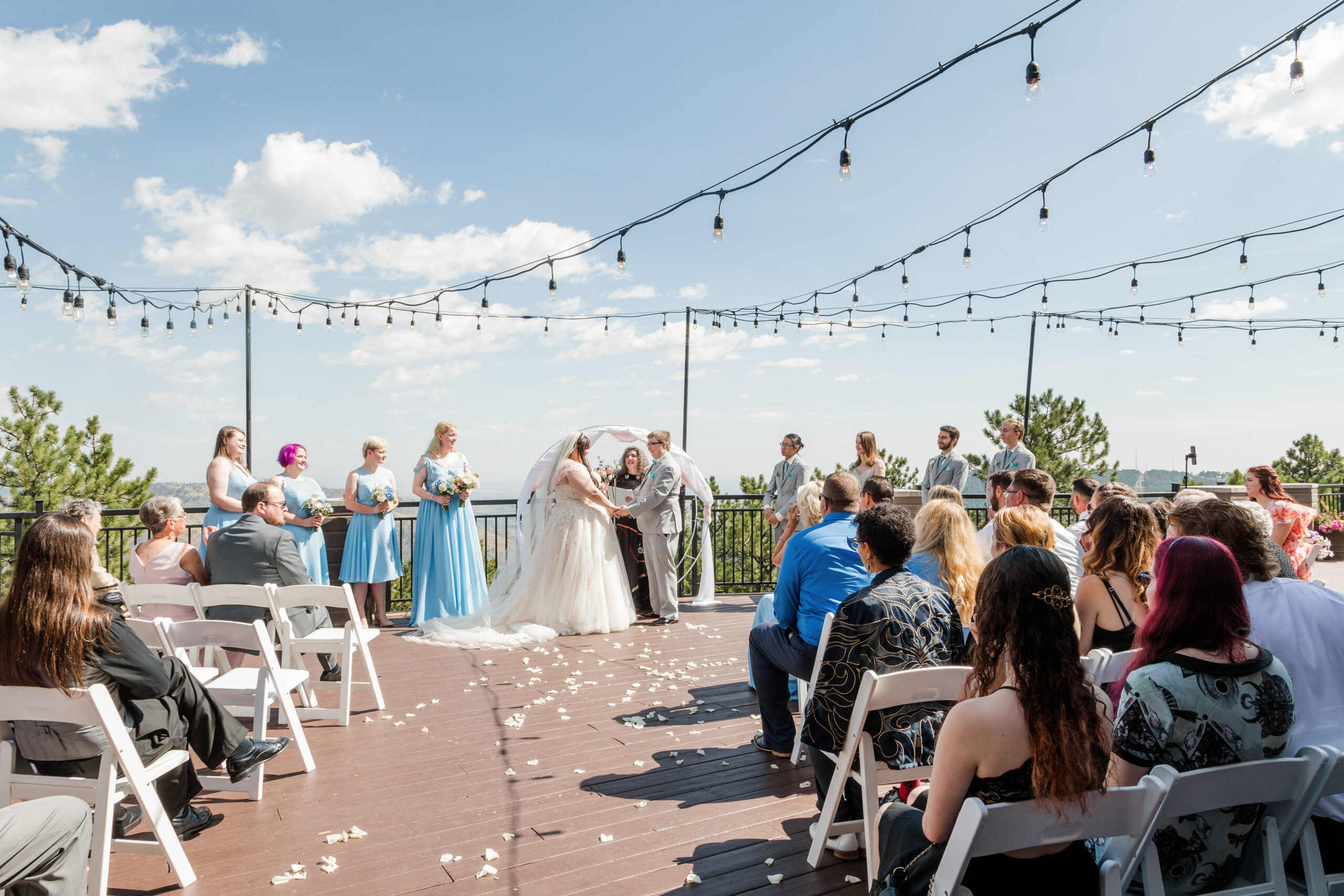 A couple holds their ceremony of their traditional timeline wedding on a deck overlooking the Colorado mountains.