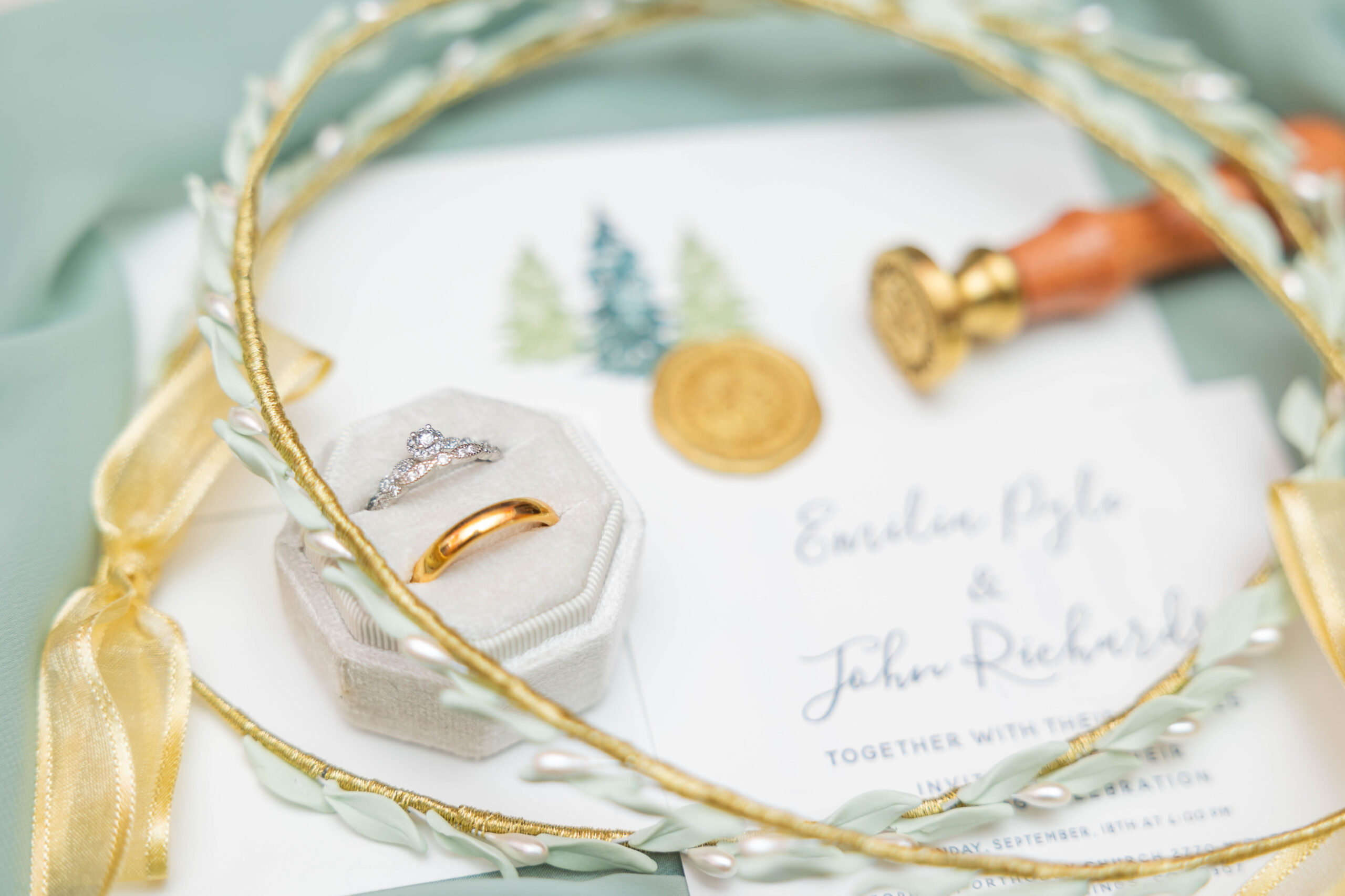 A close-up detail shot of rings, invites, and crowns at a traditional timeline wedding.