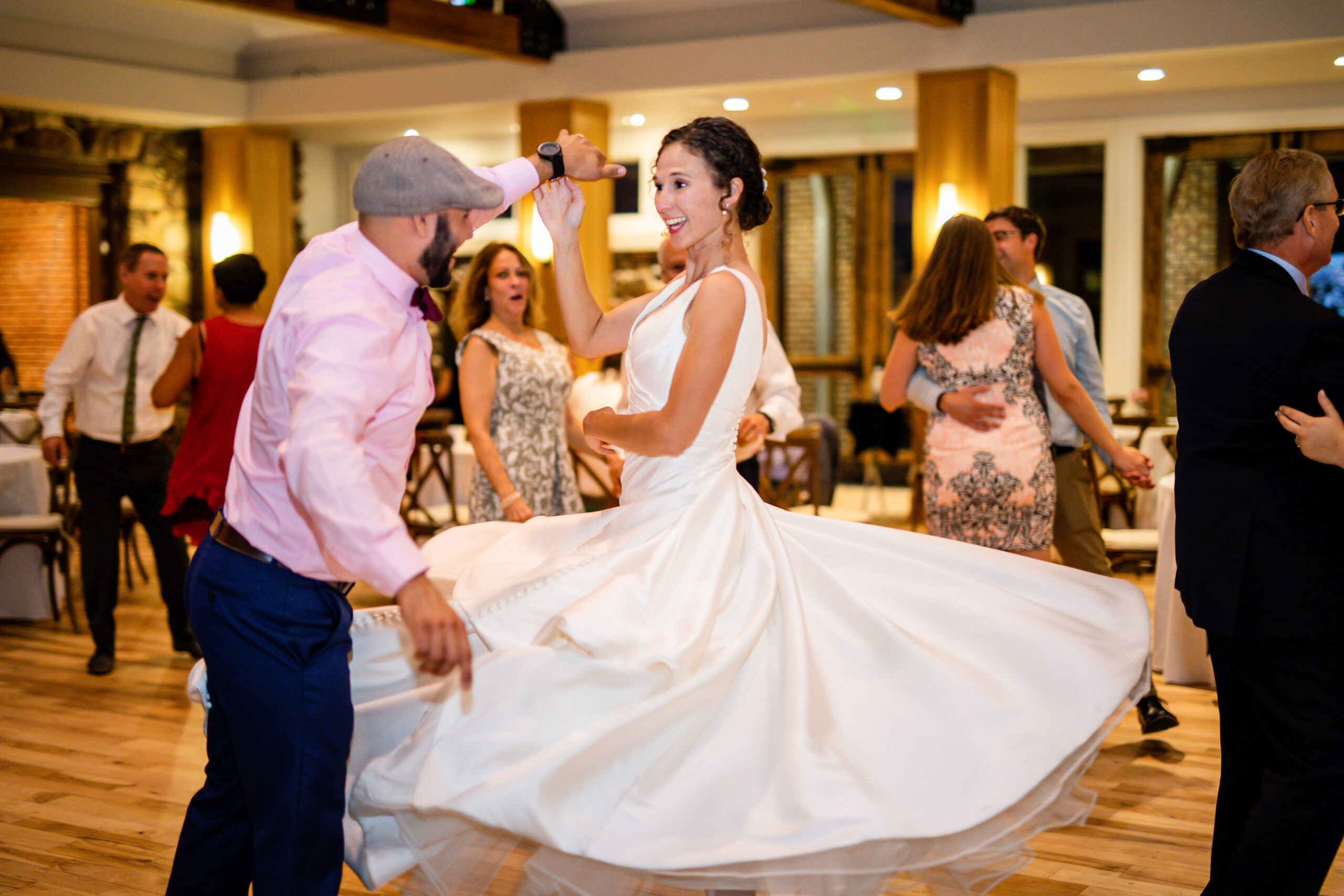 A couple dances at their wedding reception, her dress twirls beautifully.