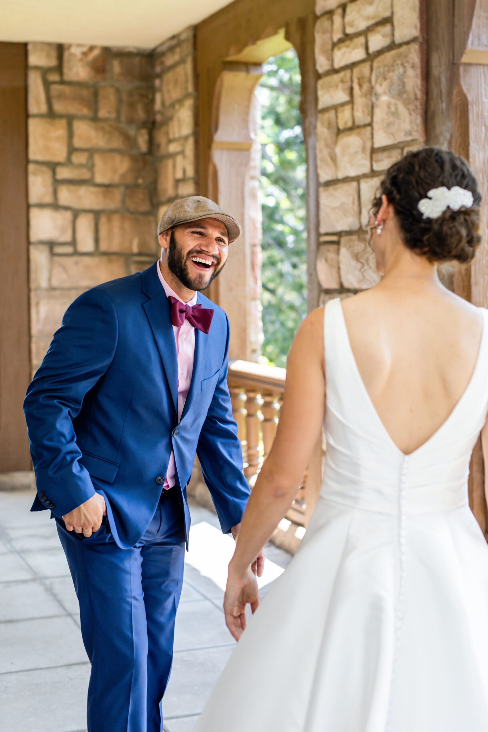 A couple has a first look in a castle venue, the man is wearing a blue suit and the woman is wearing a white dress.