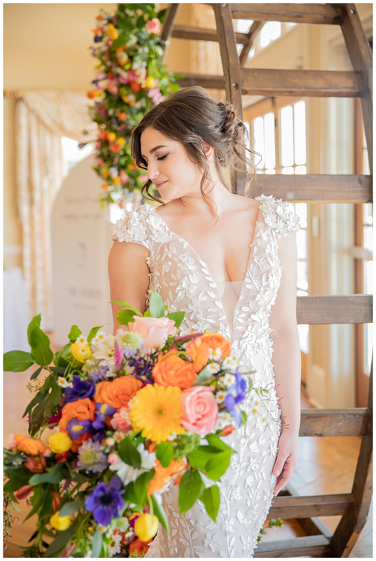 A bride poses in front of a circular wedding arch covered in colorful wildflowers in this spring wedding inspiration shoot.