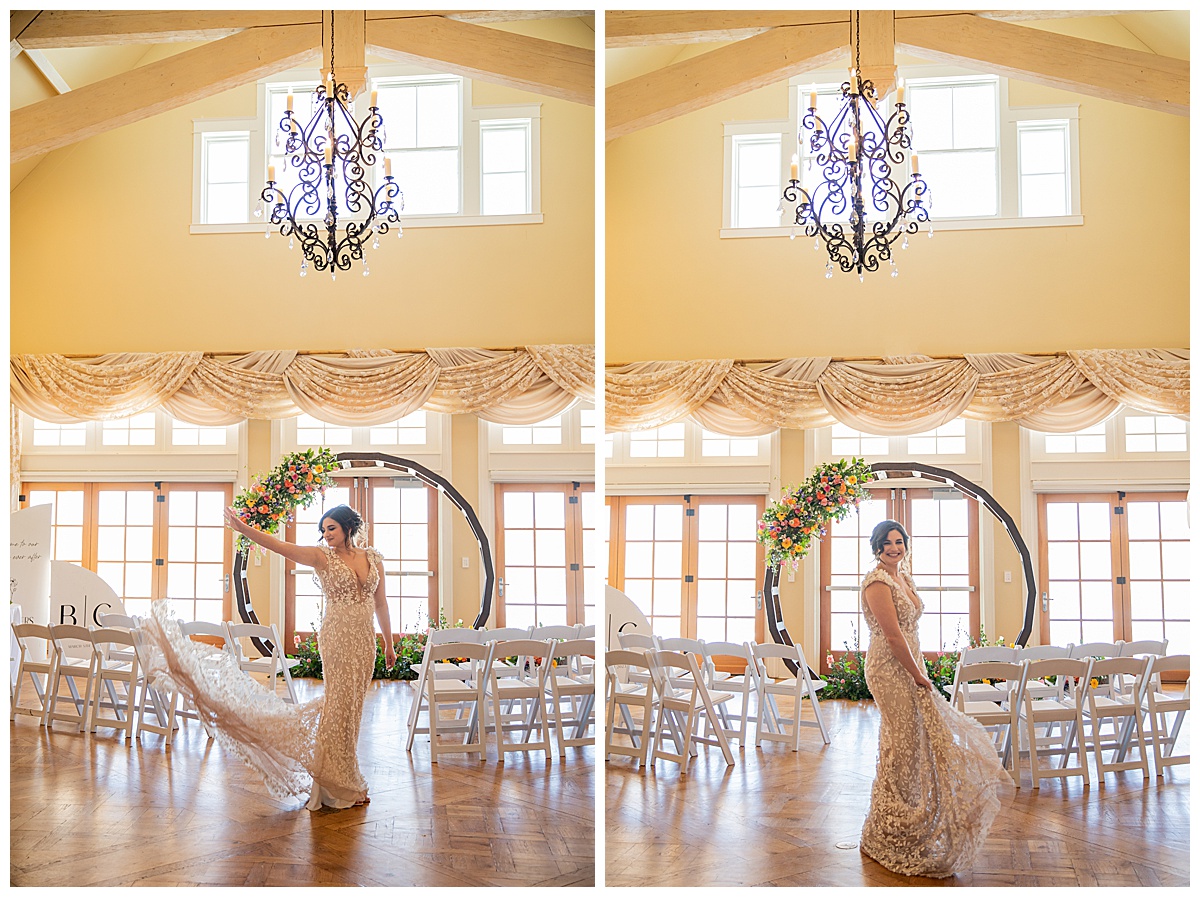 A bride poses in front of a wedding arch and chairs under a chandelier.