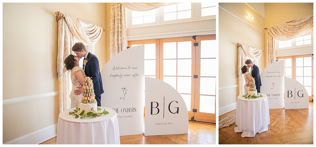 A bride and groom pose by their signs and macaron tower.