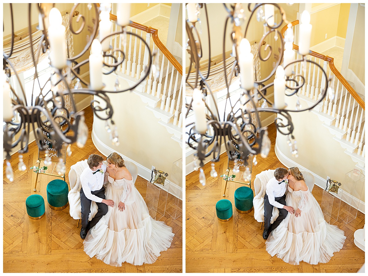 A man and woman sit next to their reception set up at this winter wedding inspiration shoot. They kiss on the couch and the photo is taken from above, near the ceiling.