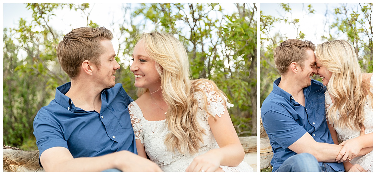 A couple poses for their portraits. The man is wearing a blue button up shirt. The woman is blond and wearing a white lace dress.