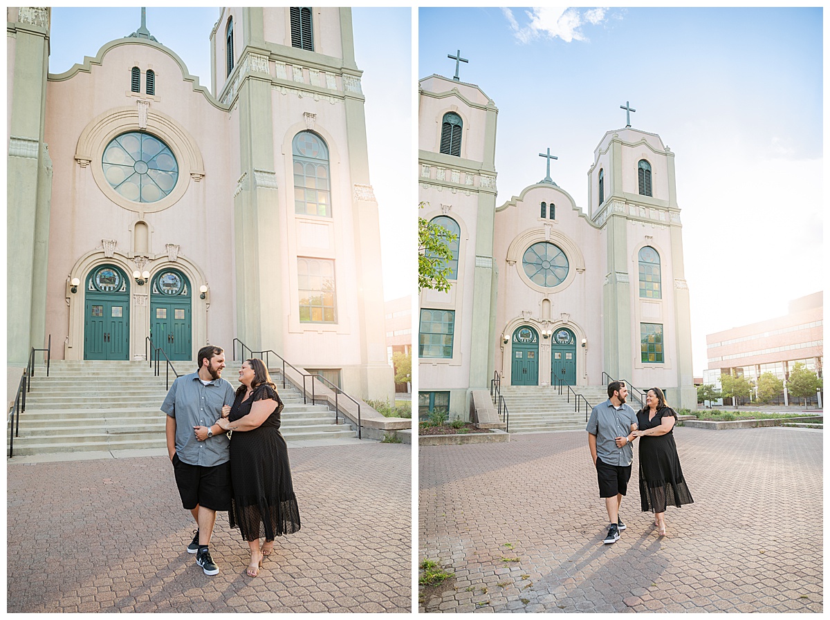 A couple in black and gray pose in front of an old pink and green church