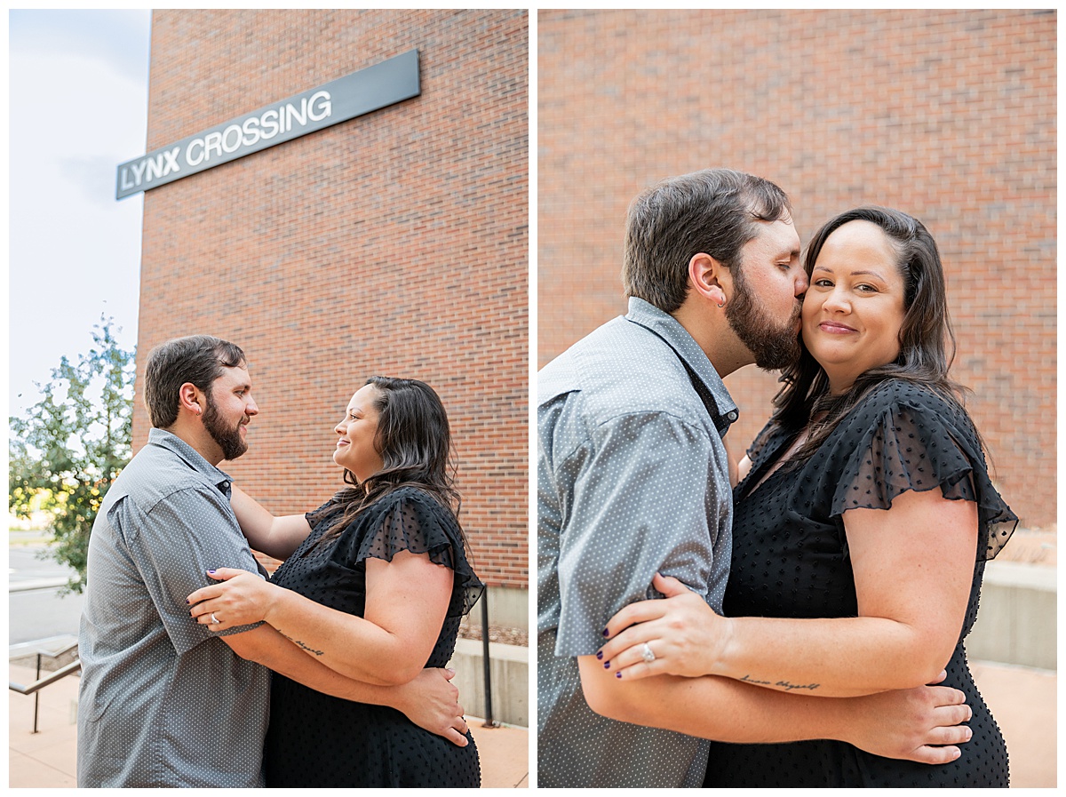 A couple in black and gray pose in front of a red brick dorm building for their Auraria Campus engagement session