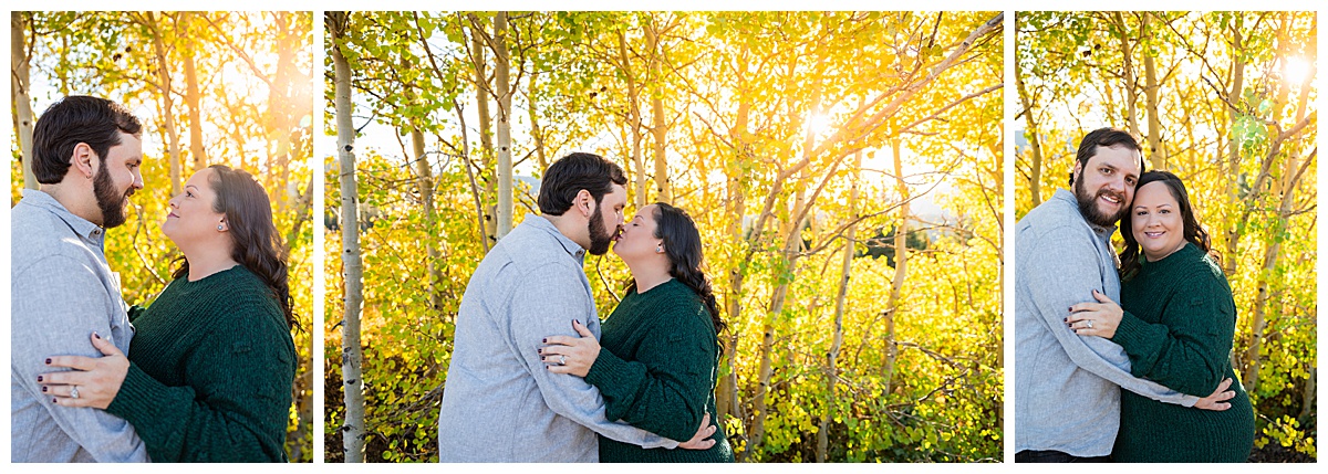 A couple poses in front of yellow aspen trees. The man is wearing a long sleeve gray button down shirt and the woman is wearing a dark green sweater