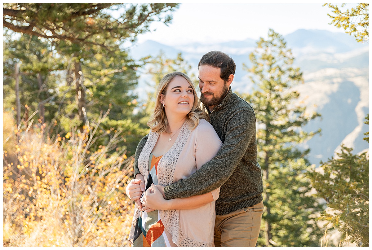 A couple poses for their Lookout Mountain couples session. The woman is wearing a geometric print shirt with a sweater and the man is wearing a green sweater and khaki pants.