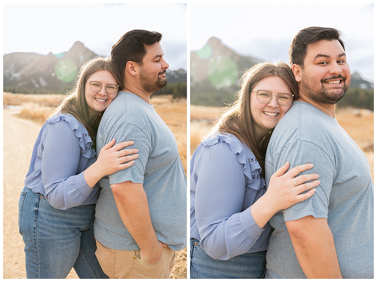 A couple poses in front of the Flatirons for their Boulder engagement session. They are both wearing blue; the man has dark brown hair and a beard, the woman has long brown hair and glasses.