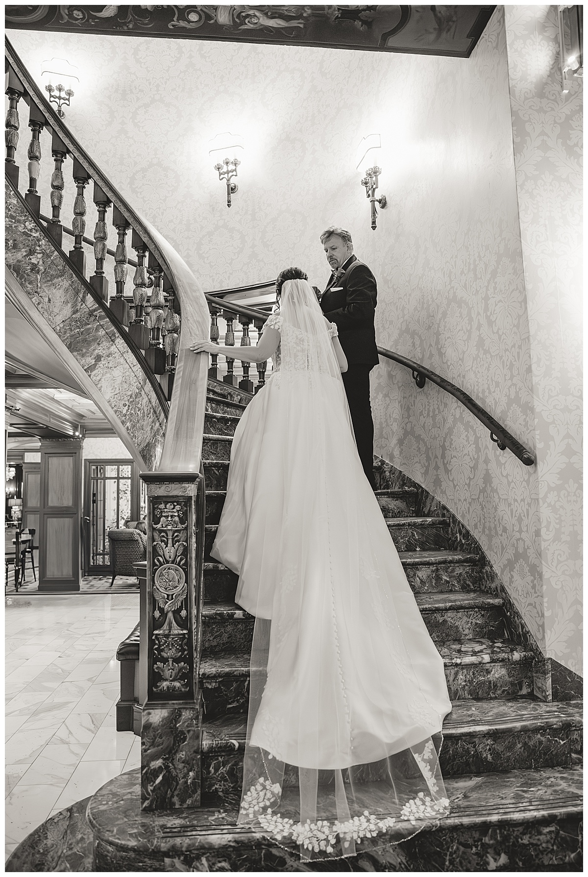 A black & white photo of the bride and groom walking up the grand staircase during their Broadmoor wedding
