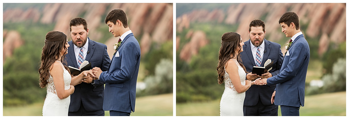 The couple hold hands during their wedding ceremony. Their bridal party is standing next to them and their guests are seated. The red rocks and golf course are in the background.