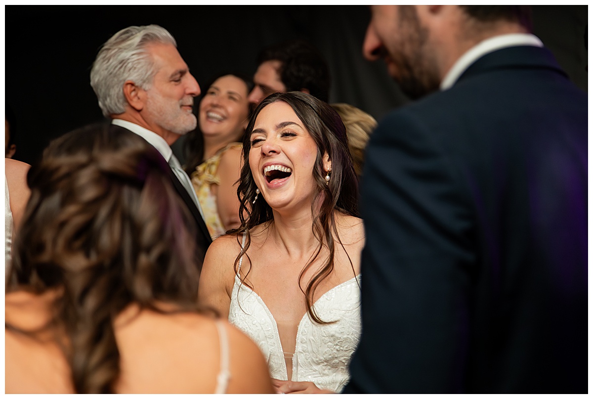 The bride, groom, and guests party during the reception. They are dancing on the dance floor, laughing, and posing for the camera.