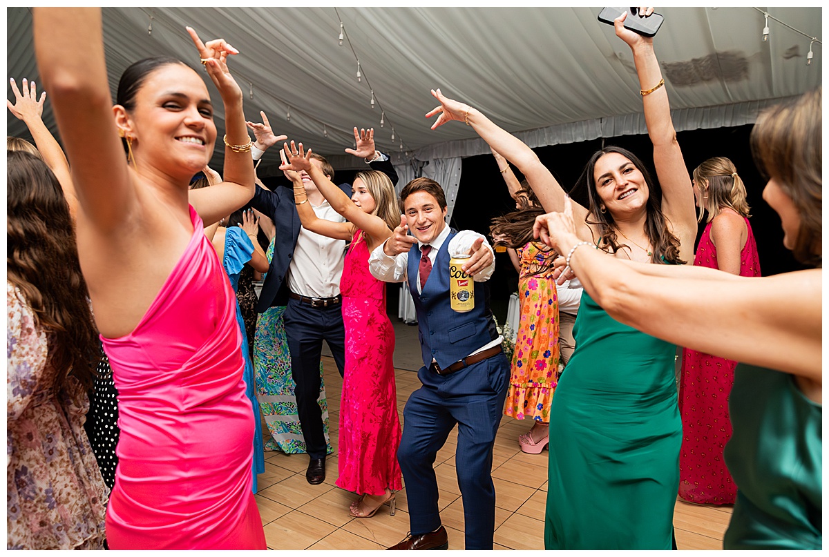 The bride, groom, and guests party during the reception. They are dancing on the dance floor, laughing, and posing for the camera.