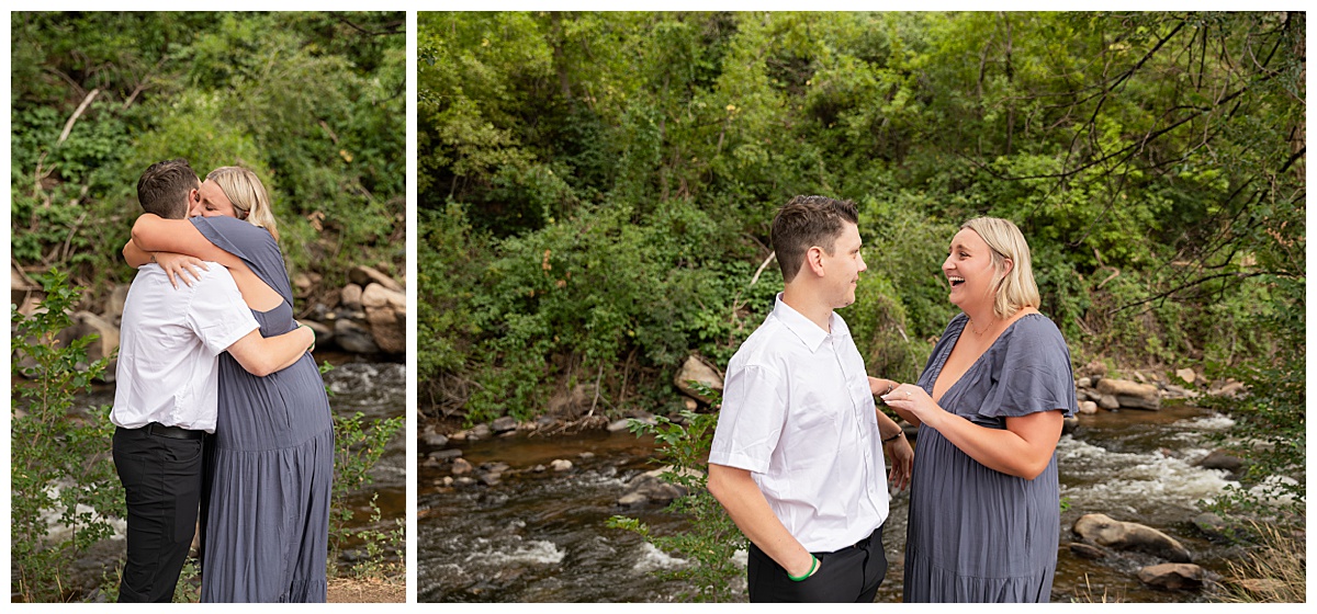 The couple celebrates after the proposal. He is wearing black slacks and a short sleeve, white button-down. She has short blonde hair and is wearing a long blue dress. There are green trees and a river in the background.