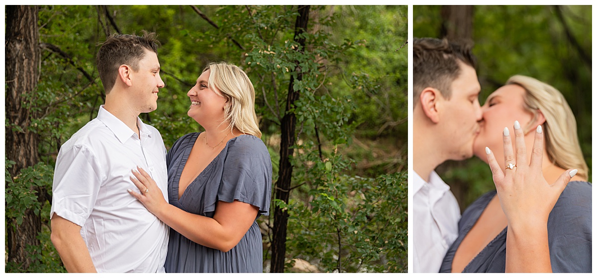 The couple celebrates after the proposal. He is wearing black slacks and a short sleeve, white button-down. She has short blonde hair and is wearing a long blue dress. There are green trees and a river in the background.