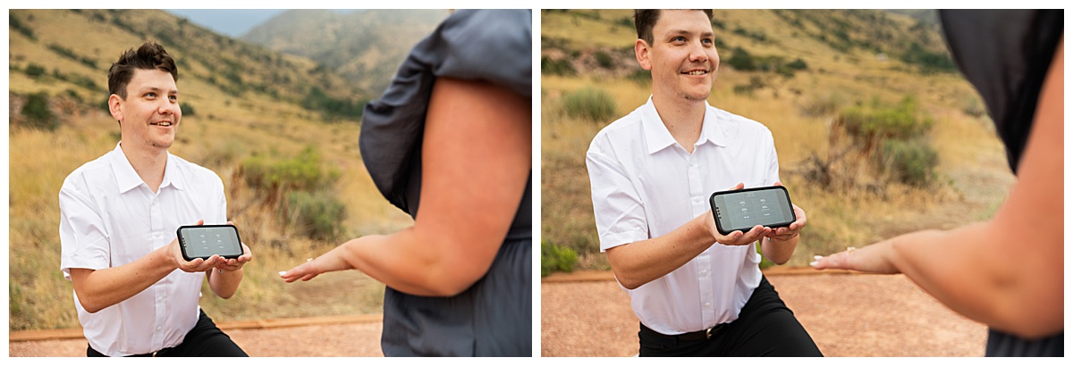 The couple takes couple's portraits. He is wearing black slacks and a short sleeve, white button-down. She has short blonde hair and is wearing a long blue dress. In a field in front of Red Rocks Amphitheater. 