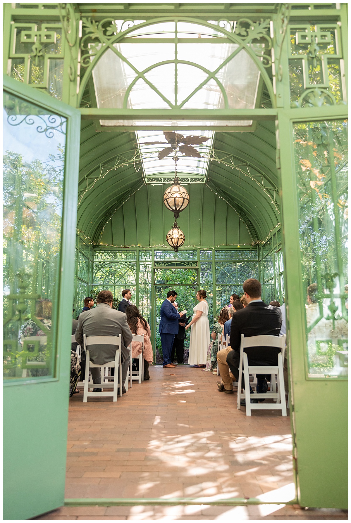 The bride and groom have their ceremony in the green metal Woodland Mosaic Solarium at their Denver Botanic Gardens wedding.