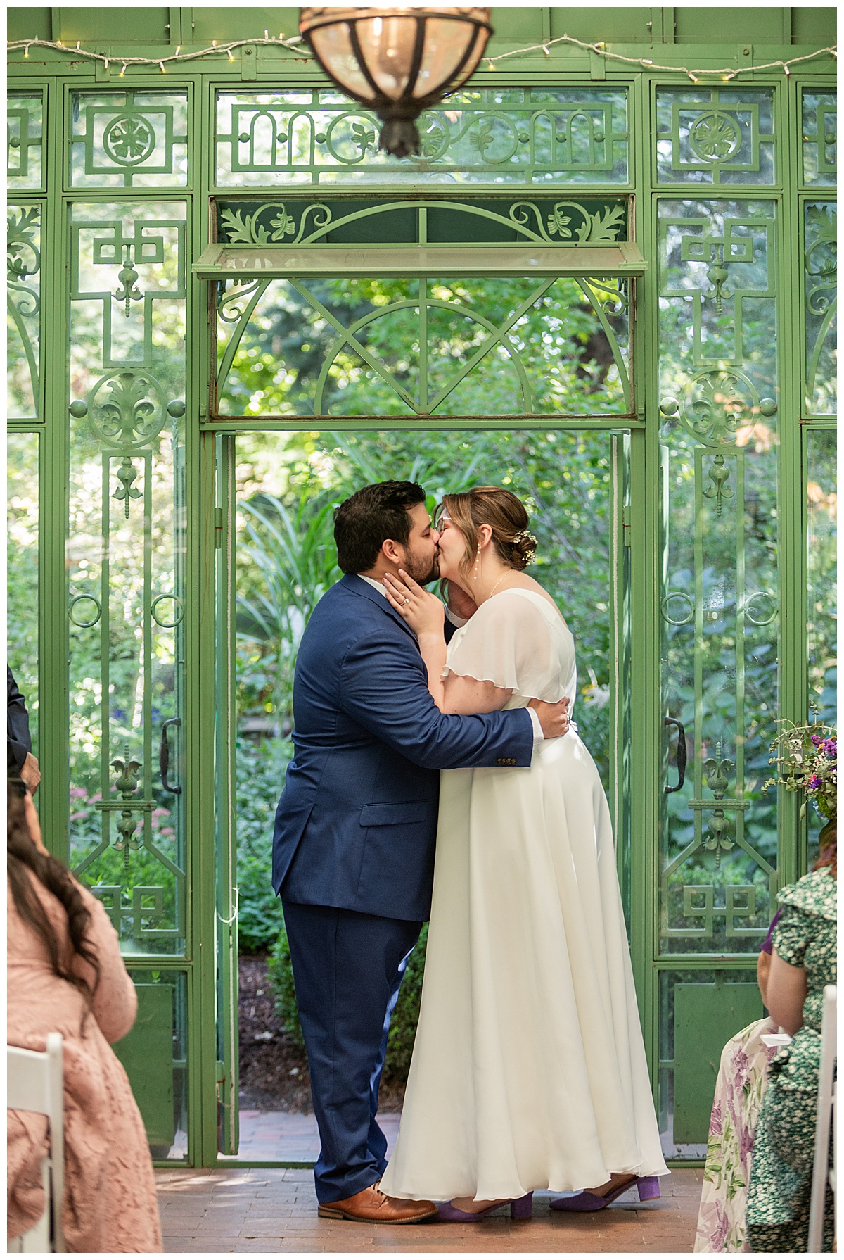 The bride and groom have their ceremony in the green metal Woodland Mosaic Solarium at their Denver Botanic Gardens wedding.