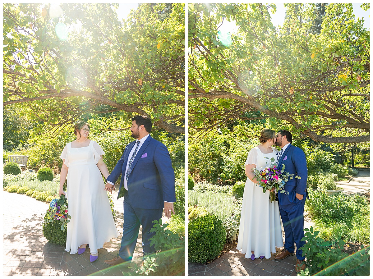 The bride and groom pose under a tree at their Denver Botanic Gardens wedding. They are looking at each other and kissing.