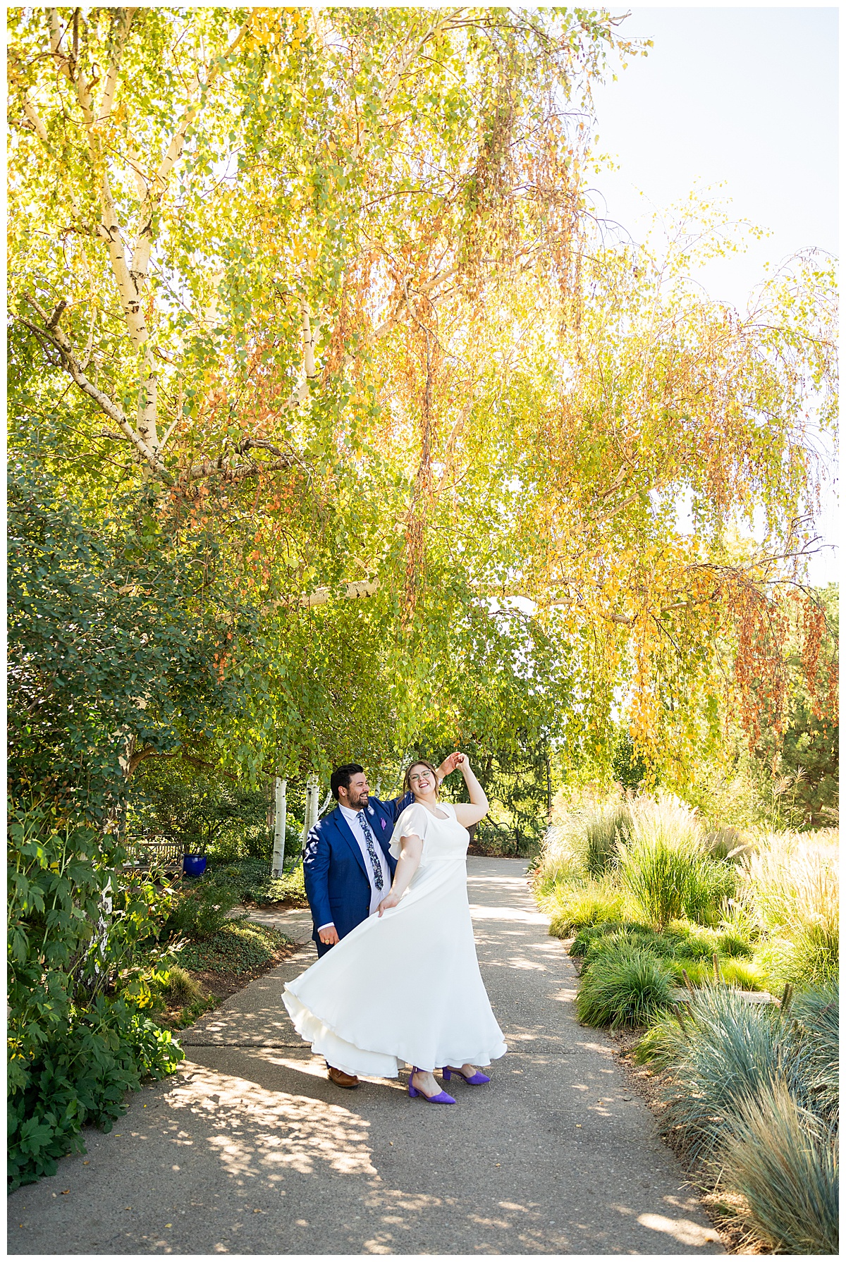 The bride and groom dance and kiss under trees starting to turn fall colors at their Denver Botanic Gardens wedding.