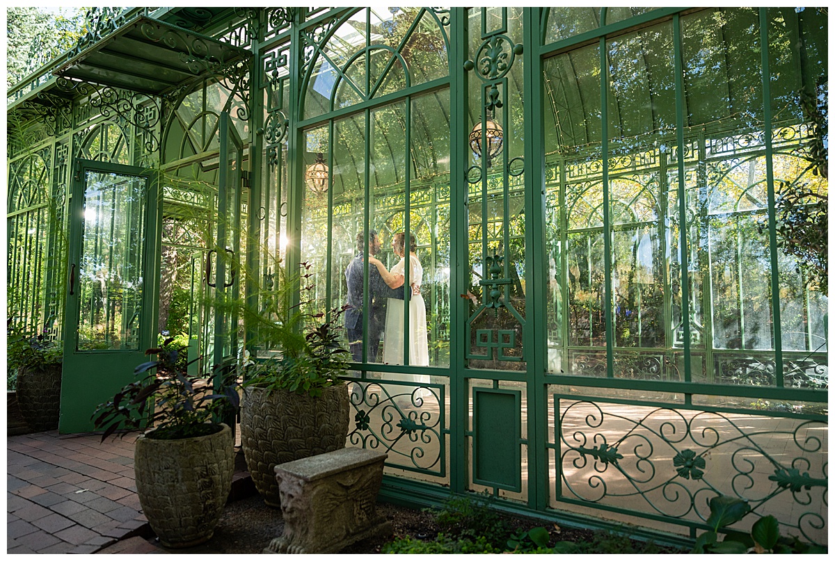 The bride and groom dance inside the green metal Woodland Mosaic Solarium. The solarium is empty now.