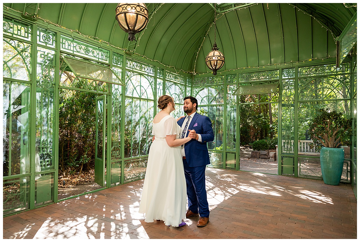 The bride and groom dance inside the green metal Woodland Mosaic Solarium. The solarium is empty now.