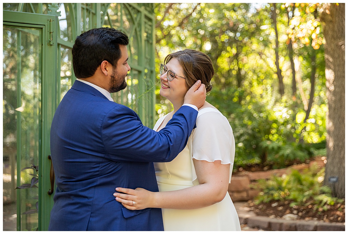 The bride and groom enjoy the last moments of their wedding day in front of the green metal and glass woodland mosaic solarium.