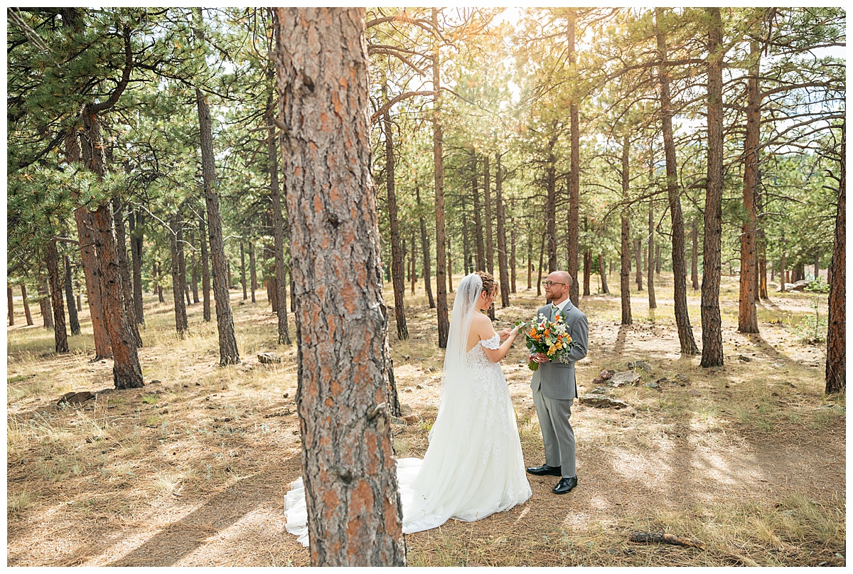 Photos of the bride and groom doing their first look for their Lookout Mountain wedding. They are standing in a pine forest.