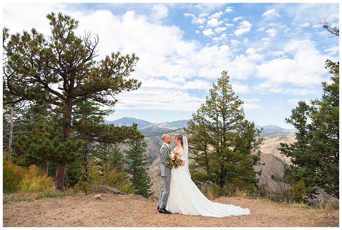 Photos of the bride and groom taking their bridal portraits for their Lookout Mountain wedding. They are posing in front of pine trees and the Rocky Mountain range in the background.