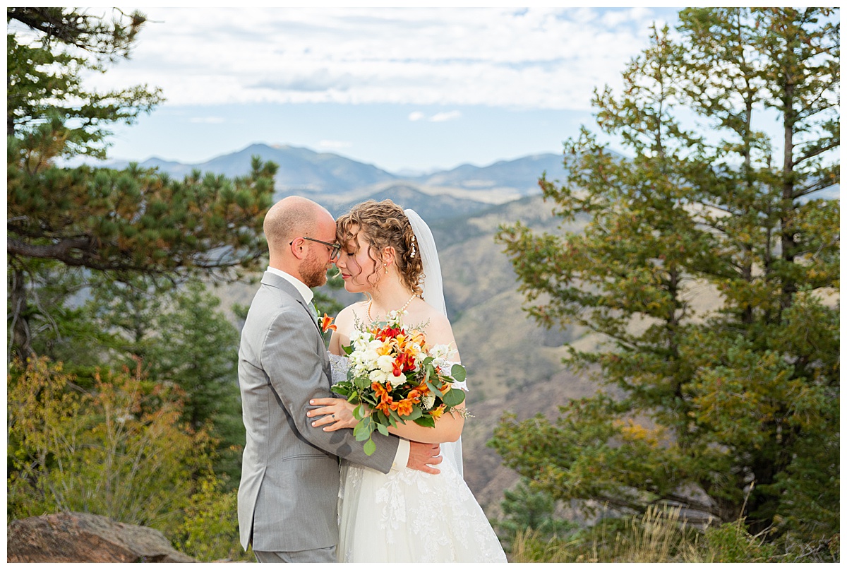 Photos of the bride and groom taking their bridal portraits for their Lookout Mountain wedding. They are posing in front of pine trees and the Rocky Mountain range in the background.