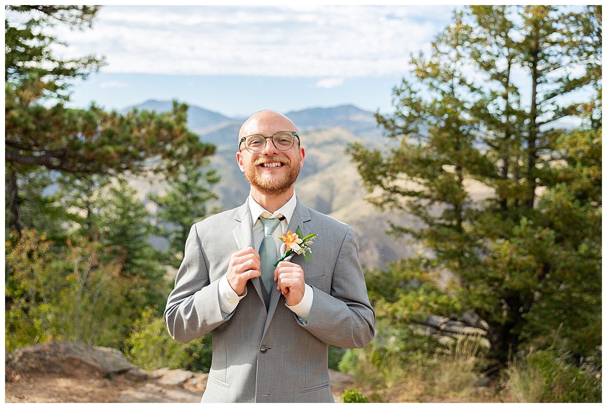 Photos of the bride and groom taking their bridal portraits for their Lookout Mountain wedding. They are posing in front of pine trees and the Rocky Mountain range in the background.
