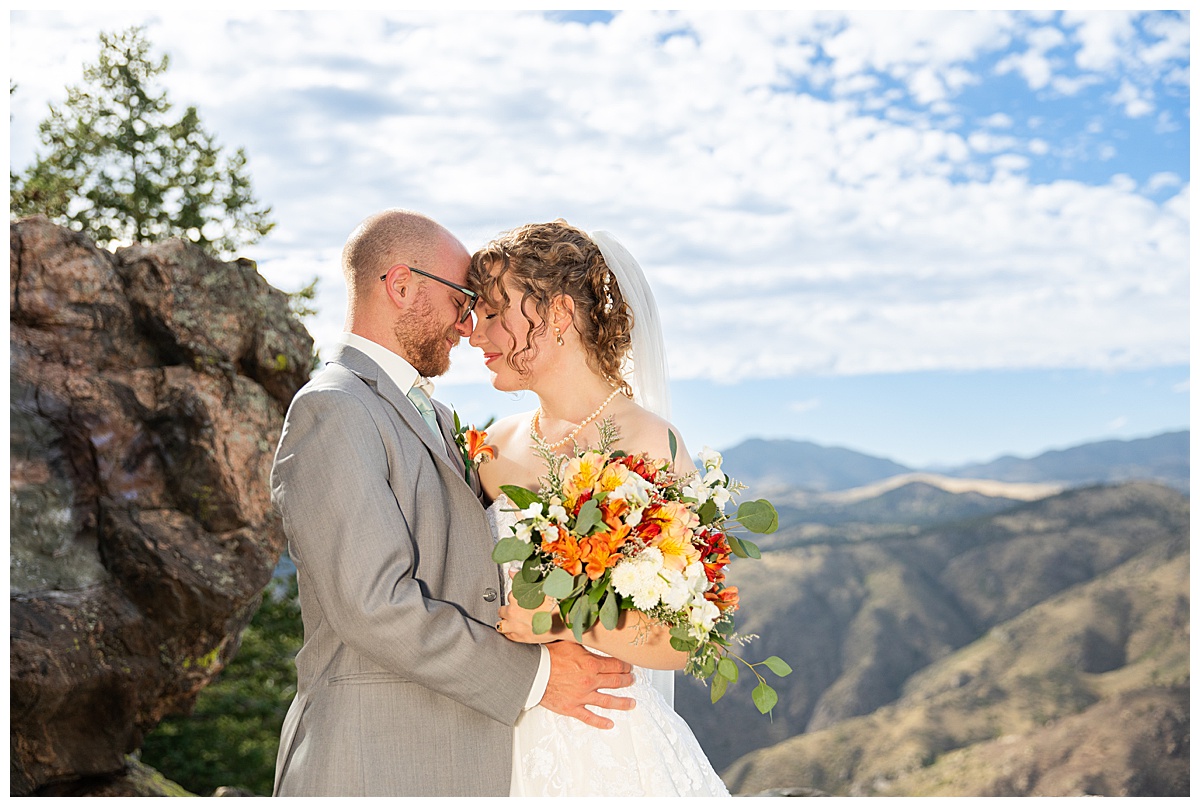 Photos of the bride and groom taking their bridal portraits for their Lookout Mountain wedding. They are posing in front of pine trees and the Rocky Mountain range in the background.