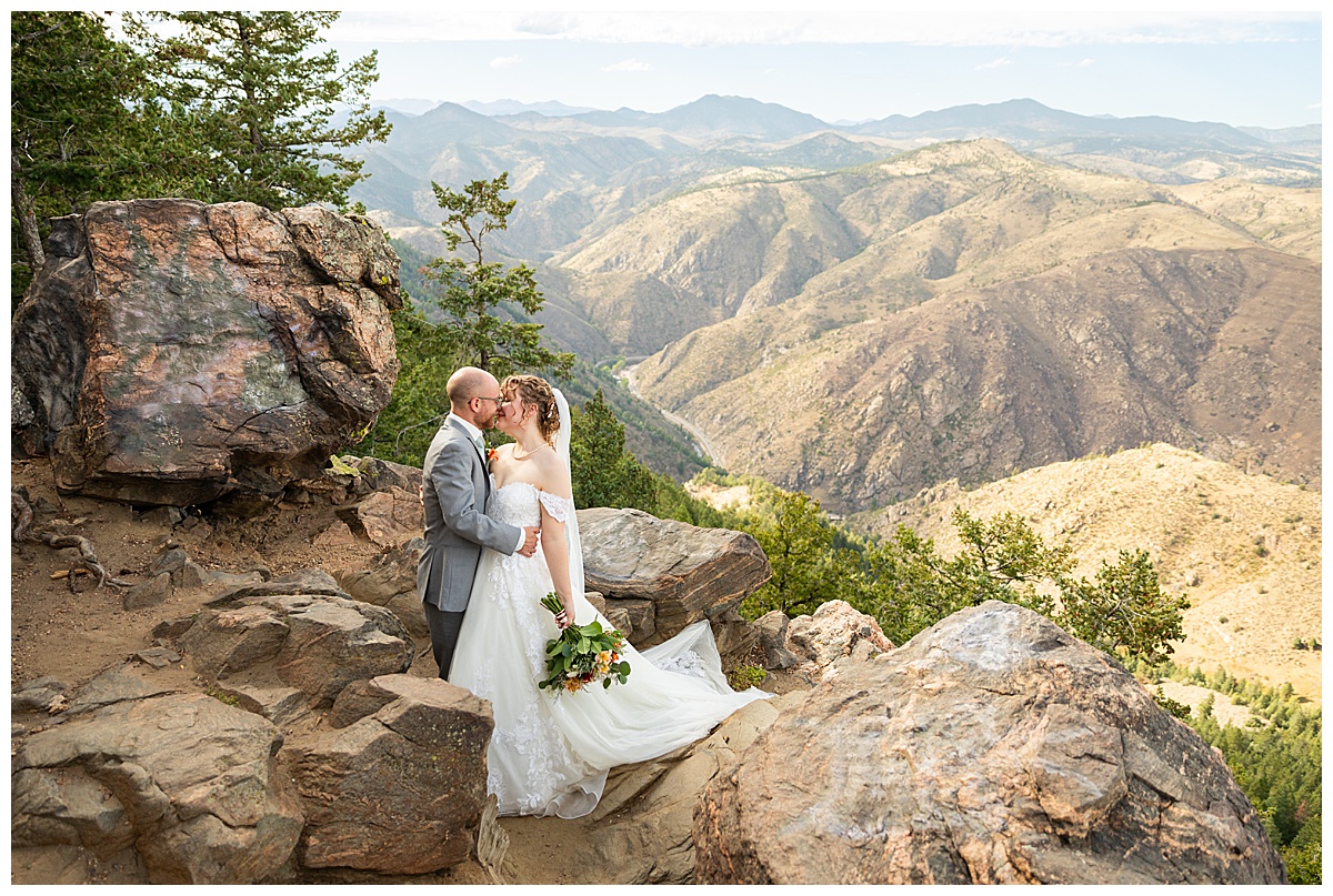 Photos of the bride and groom taking their bridal portraits for their Lookout Mountain wedding. They are posing in front of pine trees and the Rocky Mountain range in the background.
