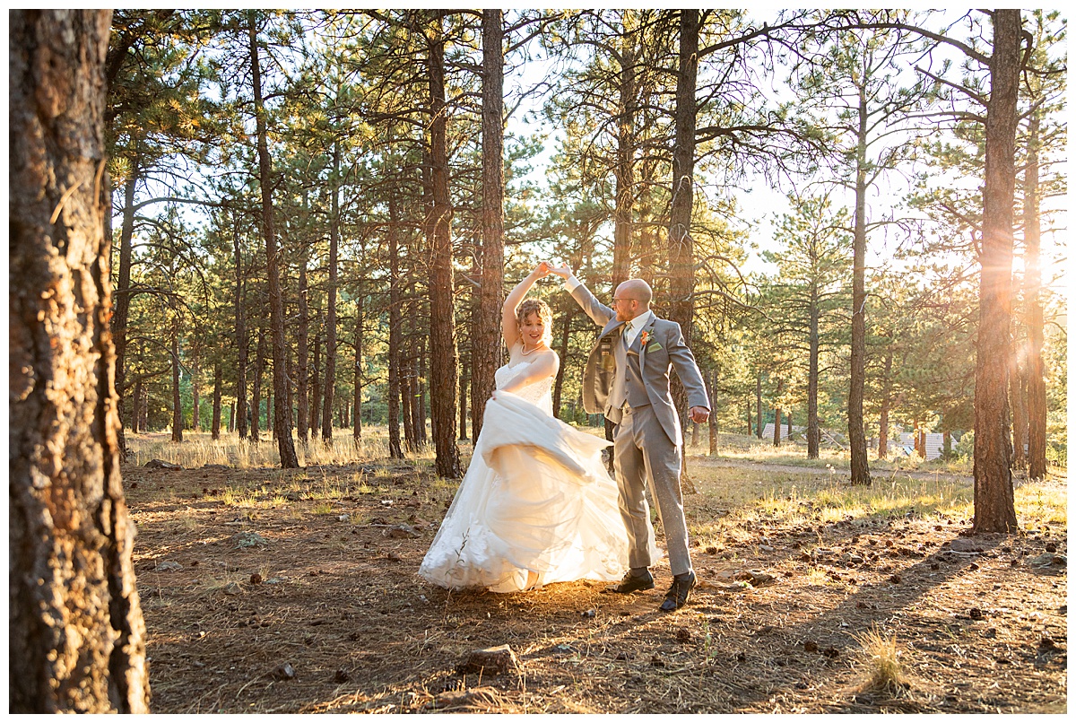 Golden hour photos of the bride and groom just outside Boettcher Mansion. They are posing in a forest of pine trees with golden light behind them.