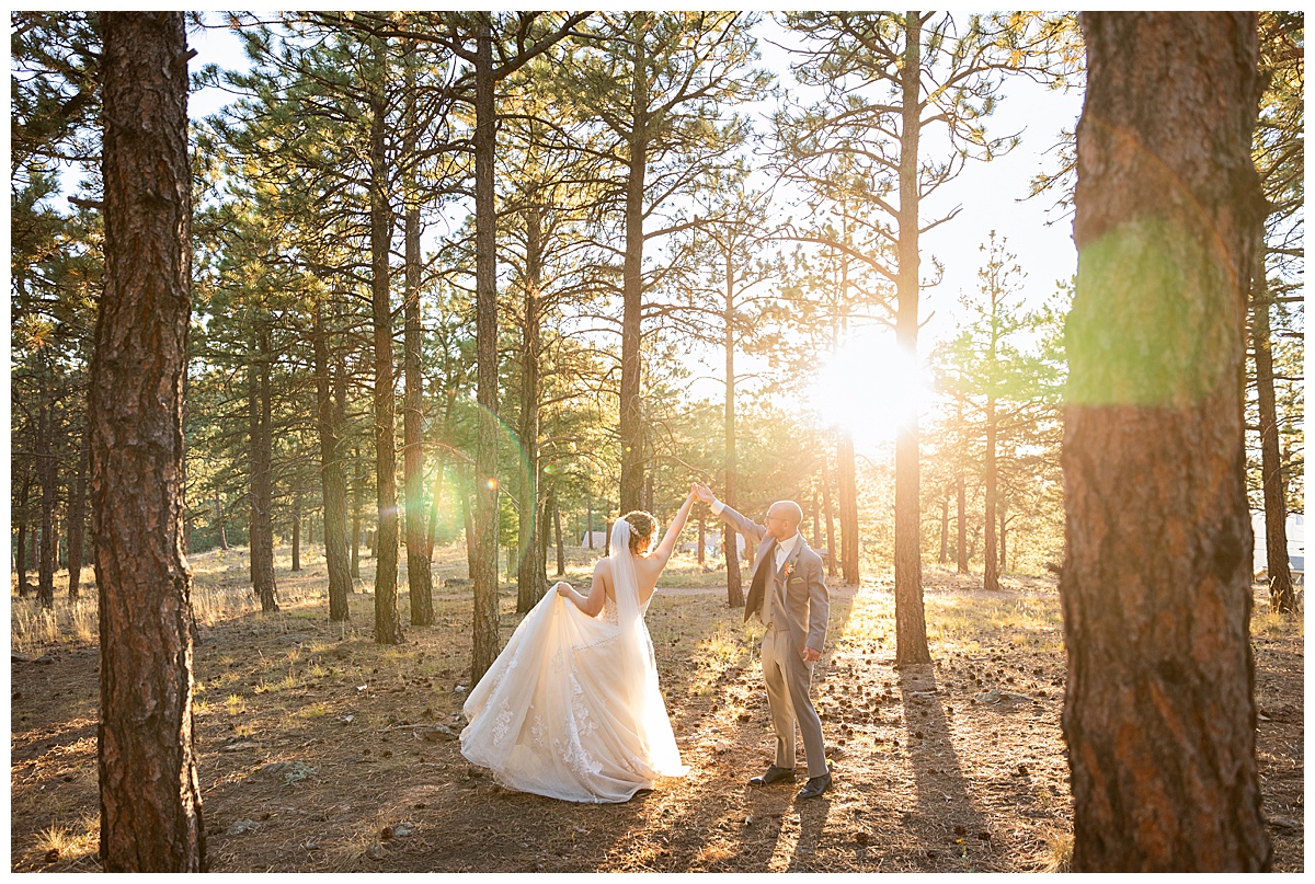Golden hour photos of the bride and groom just outside Boettcher Mansion. They are posing in a forest of pine trees with golden light behind them.