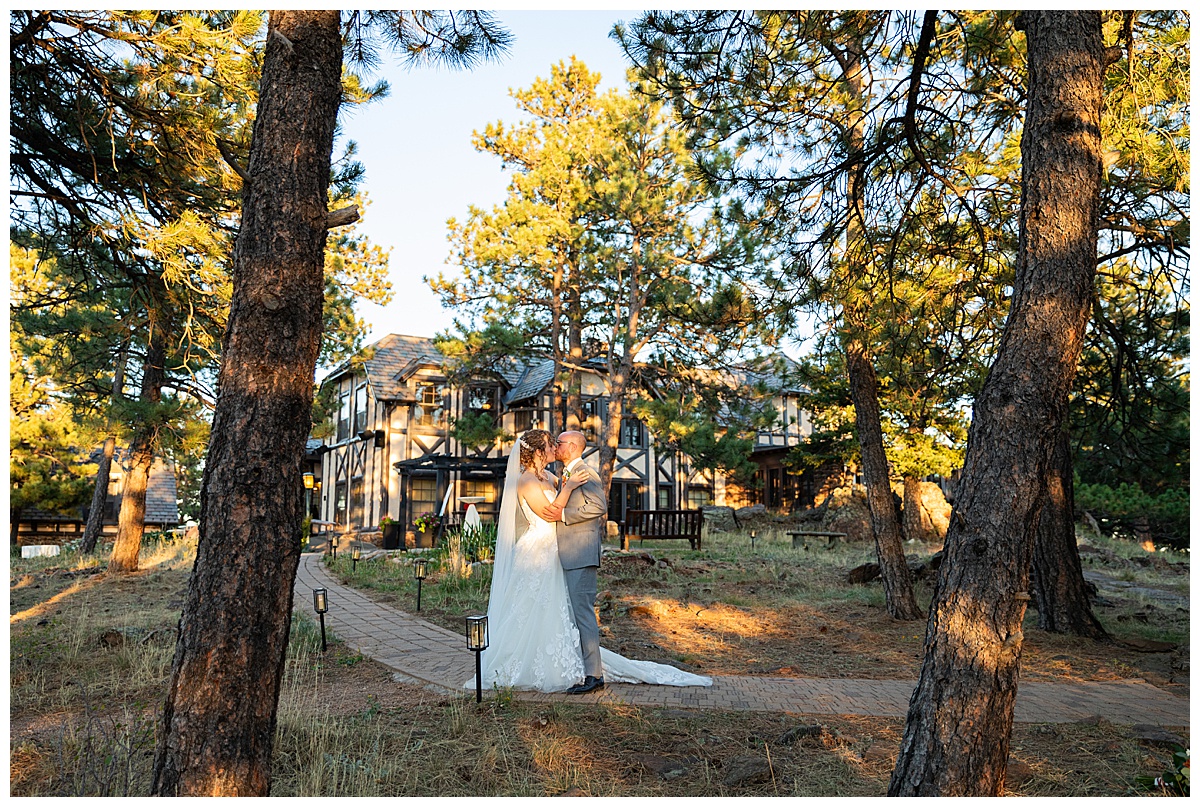 Golden hour photos of the bride and groom just outside Boettcher Mansion. They are posing in a forest of pine trees with golden light behind them.