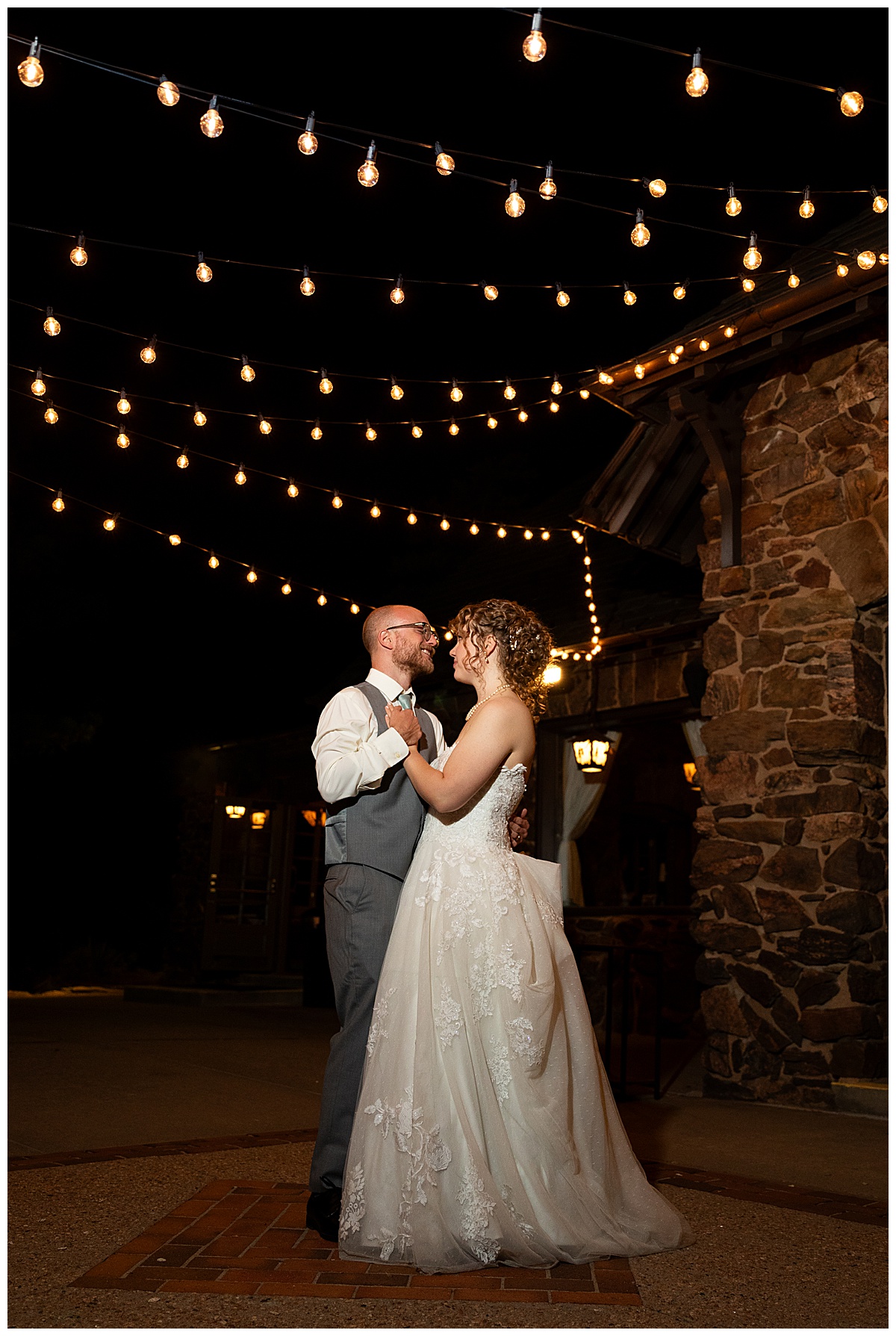 The bride and groom share a private last dance in the dark outside the Boettcher Mansion under fairy lights.