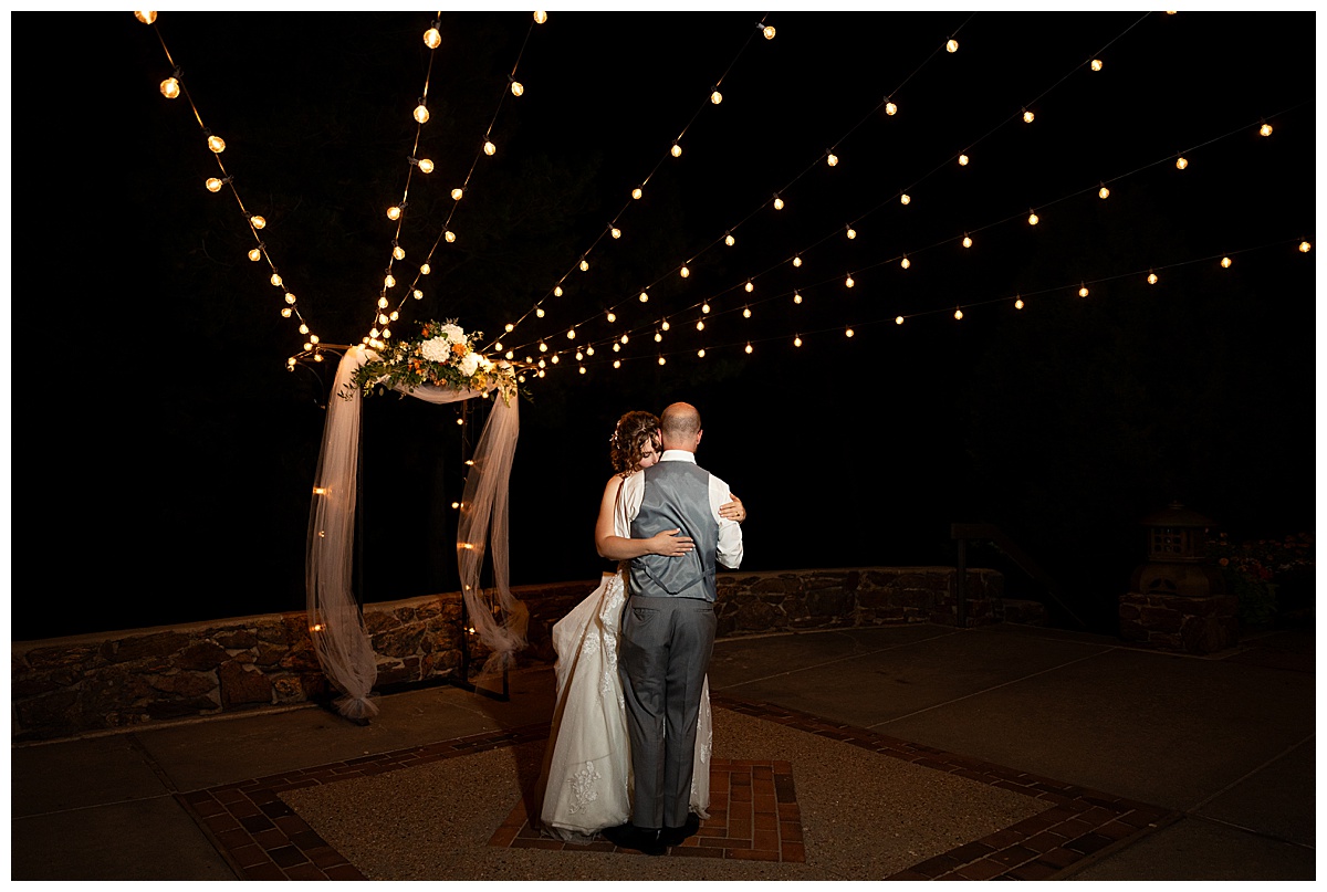 The bride and groom share a private last dance in the dark outside the Boettcher Mansion under fairy lights.
